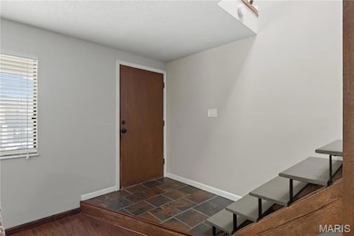 Foyer entrance with dark stone finish flooring and a textured ceiling