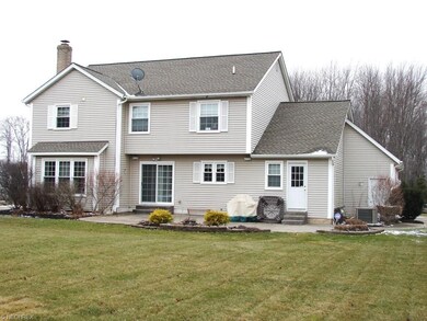 back of home with large stamped patio & sliders to