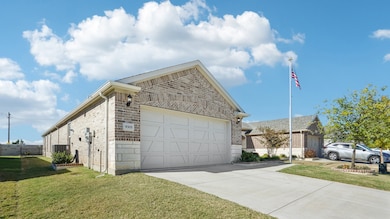 View of front of property featuring brick siding, a front yard, concrete driveway, and an attached garage