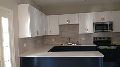 Kitchen featuring white cabinetry, appliances with stainless steel finishes, and tasteful backsplash