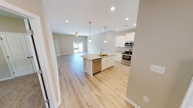 Kitchen with open floor plan, white cabinets, a kitchen island with sink, recessed lighting, and decorative light fixtures