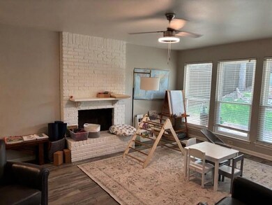Living room with wood finished floors, a brick fireplace, and a ceiling fan