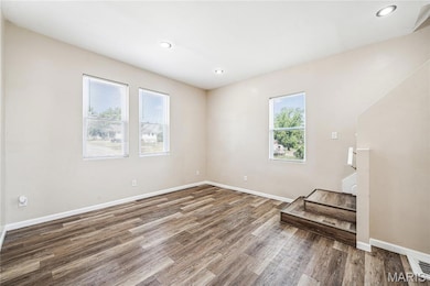 Living room with recessed lighting, wood finished floors, and stairs.