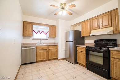 Kitchen with stainless steel appliances, under cabinet range hood, light countertops, light floors, and a ceiling fan