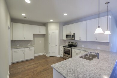 Kitchen off of the dining room and living room. Countertop overhang allows for bar stool seating. Plenty of countertops, tile backsplash, and stainless steel appliances.  *Photo is of model home of the same floor plan. Colors and options may vary.