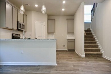 Kitchen with gray cabinetry, stainless steel microwave, recessed lighting, wood finished floors, and backsplash