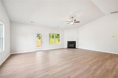 Unfurnished living room featuring light wood-style flooring, lofted ceiling, a fireplace with flush hearth, and ceiling fan