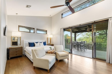 Bedroom featuring access to exterior, wood finished floors, a ceiling fan, and a towering ceiling