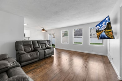 Living area with wood finished floors, a textured ceiling, and ceiling fan
