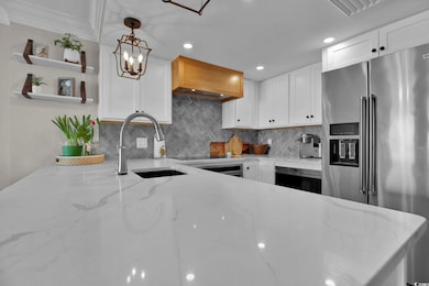 Kitchen with tasteful backsplash, white cabinetry,