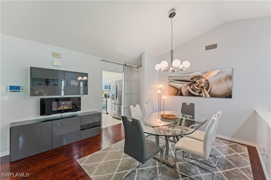 Dining area with dark wood-type flooring, vaulted