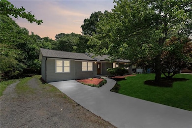 Ranch-style home featuring driveway, a front lawn, and roof with shingles