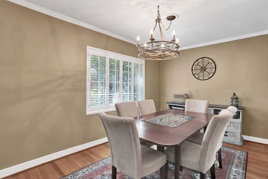 Dining room with baseboards, a chandelier, wood finished floors, and ornamental molding