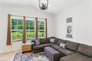 Living area with a chandelier, vaulted ceiling, and crown molding