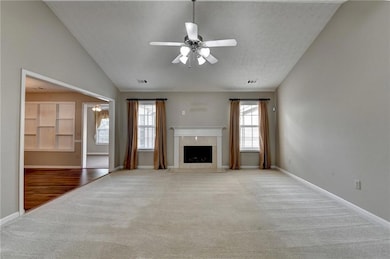 Unfurnished living room with carpet floors, ceiling fan, a high end fireplace, baseboards, and a textured ceiling
