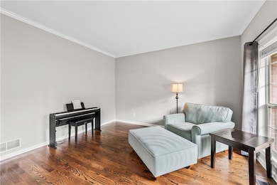 Sitting room with ornamental molding, wood finished floors, and baseboards