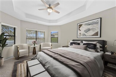 Carpeted bedroom featuring a raised ceiling, multiple windows, and ceiling fan