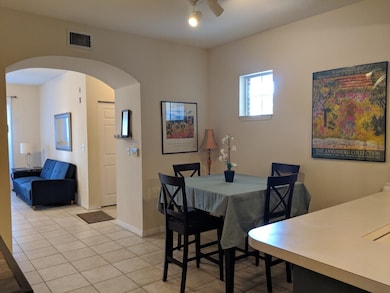 Dining area featuring arched walkways, light tile patterned floors, and ceiling fan
