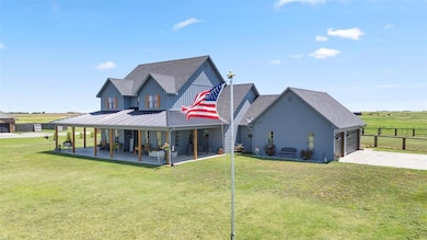 Rear view of house featuring driveway, a shingled roof, a metal roof, an attached garage, and board and batten siding