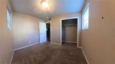 Unfurnished bedroom with dark colored carpet, a textured ceiling, and a closet