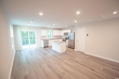 Kitchen with appliances with stainless steel finishes, a kitchen island, white cabinetry, recessed lighting, and open floor plan