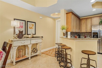 Kitchen with a breakfast bar area, baseboards, light tile patterned flooring, stainless steel refrigerator with ice dispenser, and backsplash