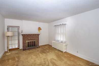 Unfurnished living room featuring light carpet, a healthy amount of sunlight, radiator heating unit, and a fireplace