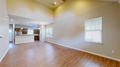 Unfurnished living room featuring light wood-style floors, a towering ceiling, and recessed lighting