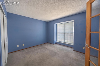 Carpeted spare room with a textured ceiling and baseboards