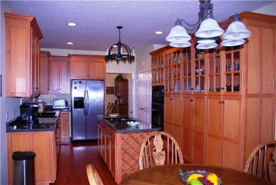 Kitchen with abundance of cabinets, an island with a cook top and hardwood floors. 
