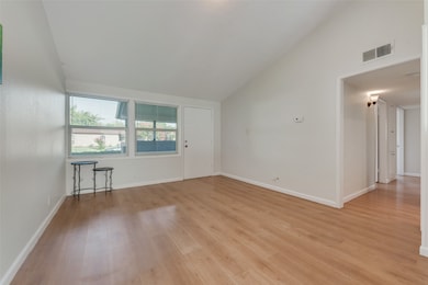 Empty room featuring light wood-type flooring and high vaulted ceiling