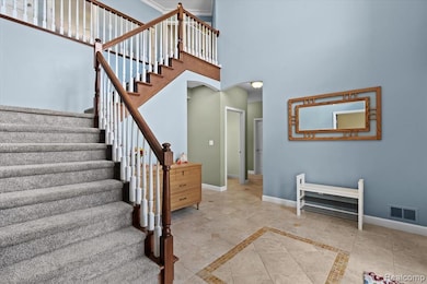 Stairs featuring a high ceiling, inlaid floor details, arched walkways, and tile patterned flooring