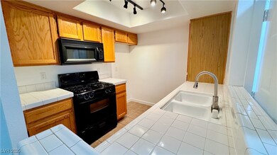 Kitchen with brown cabinets, a raised ceiling, til