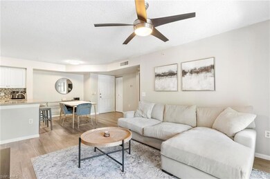 Living room with light wood-style floors, a ceiling fan, a textured ceiling, and baseboards