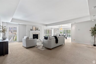 Living area featuring light carpet, a fireplace, a chandelier, and a raised ceiling