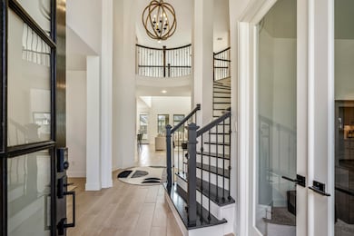 Upon entering you find a welcoming corridor showcasing beautiful contrasting details including a stunning rotunda, 19ft ceilings, and custom lighting . The entry way is bright, open, and features dark stained wood stairs and the wood-tile flooring that extends through the main living areas making it easy and clean to maintain.