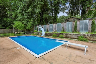 View of swimming pool with a water slide, a diving board, a fenced backyard, and a patio area