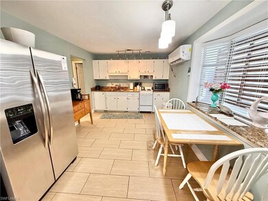 Kitchen with stainless steel appliances, a sink, a wall unit AC, track lighting, and white cabinets