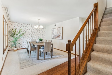 Carpeted dining area with wallpapered walls, stai