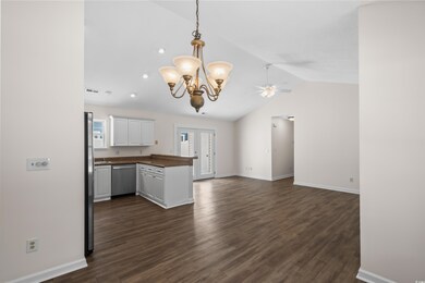 Kitchen featuring dishwasher, dark countertops, vaulted ceiling, a peninsula, and a chandelier