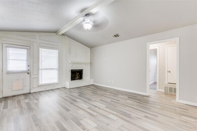 Unfurnished living room with light hardwood / wood-style flooring, ceiling fan, a brick fireplace, and lofted ceiling with beams