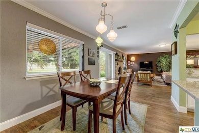 Dining area with crown molding and wood finished floors