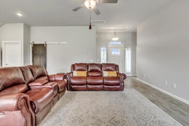 Living area featuring wood finished floors, a ceiling fan, baseboards, and a barn door