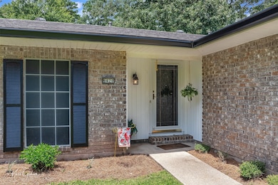 View of exterior entry featuring brick siding and a shingled roof