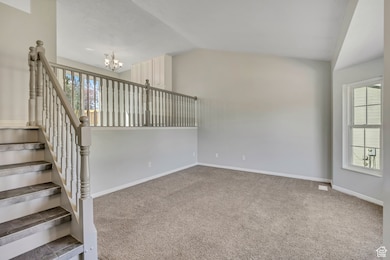 Staircase with carpet flooring, a chandelier, and lofted ceiling