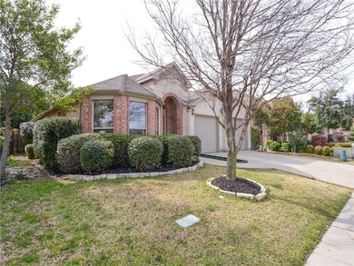 View of front of house with brick siding, concrete driveway, a front lawn, and an attached garage