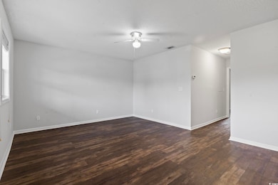 Spare room with dark wood-type flooring, ceiling fan, and a textured ceiling