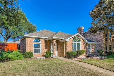 View of front of home with a shingled roof, brick siding, and a chimney