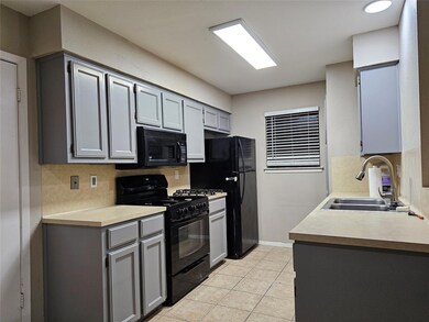 Kitchen featuring black appliances, a sink, gray 