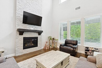 Living room featuring plenty of natural light, a high ceiling, a stone fireplace, and dark hardwood / wood-style floors